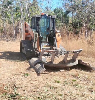 A bobcat clearing a fire break.